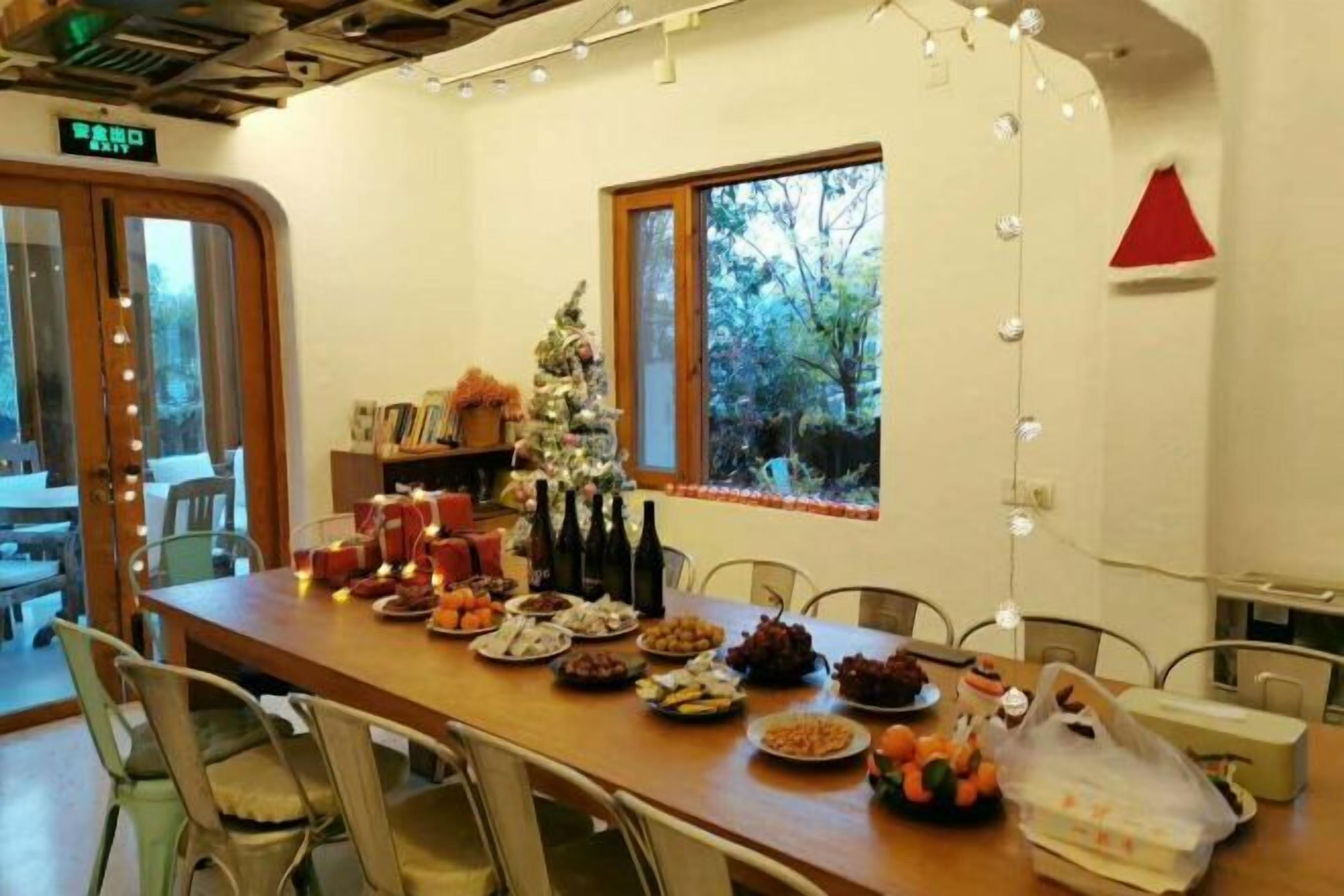A dining area with a long table set for a meal, a small Christmas tree, and string lights.