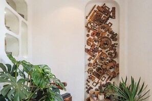 Una pared con una colección de objetos metálicos y una planta en maceta.