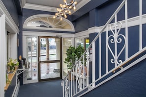 Un hall d’hôtel avec un escalier, un comptoir d’accueil et une grande fenêtre en arc de cercle.
