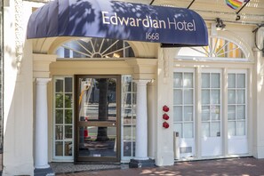 Entrada del Hotel Edwardian con fachada clásica, amplias puertas de vidrio y un toldo prominente.