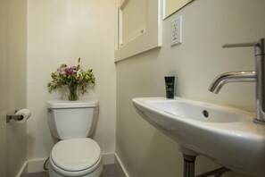 A bathroom with a toilet, a sink, and a vase of flowers. - Economy Double Room with Ensuite Bathroom (San Francisco)