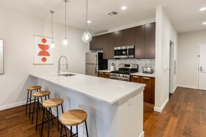 Enjoy cooking in this well-equipped kitchen with a central island, bar stools, and stainless steel appliances.