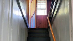 A staircase with dark steps and a wooden handrail. - Quaint quarters in South Wellfleet (Wellfleet)