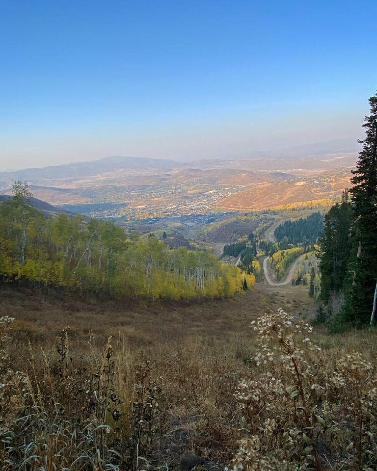 A mountainous landscape with a clear view of a valley and distant cityscape.