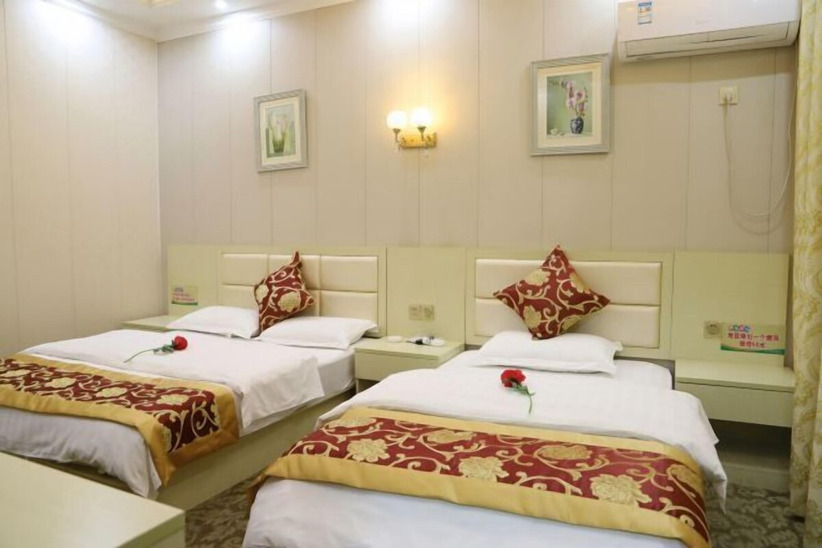 A hotel room with two single beds, each with a red rose on the bedspread.