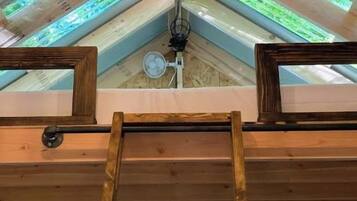 Un tragaluz con una escalera de madera que conduce a un ventilador de techo.