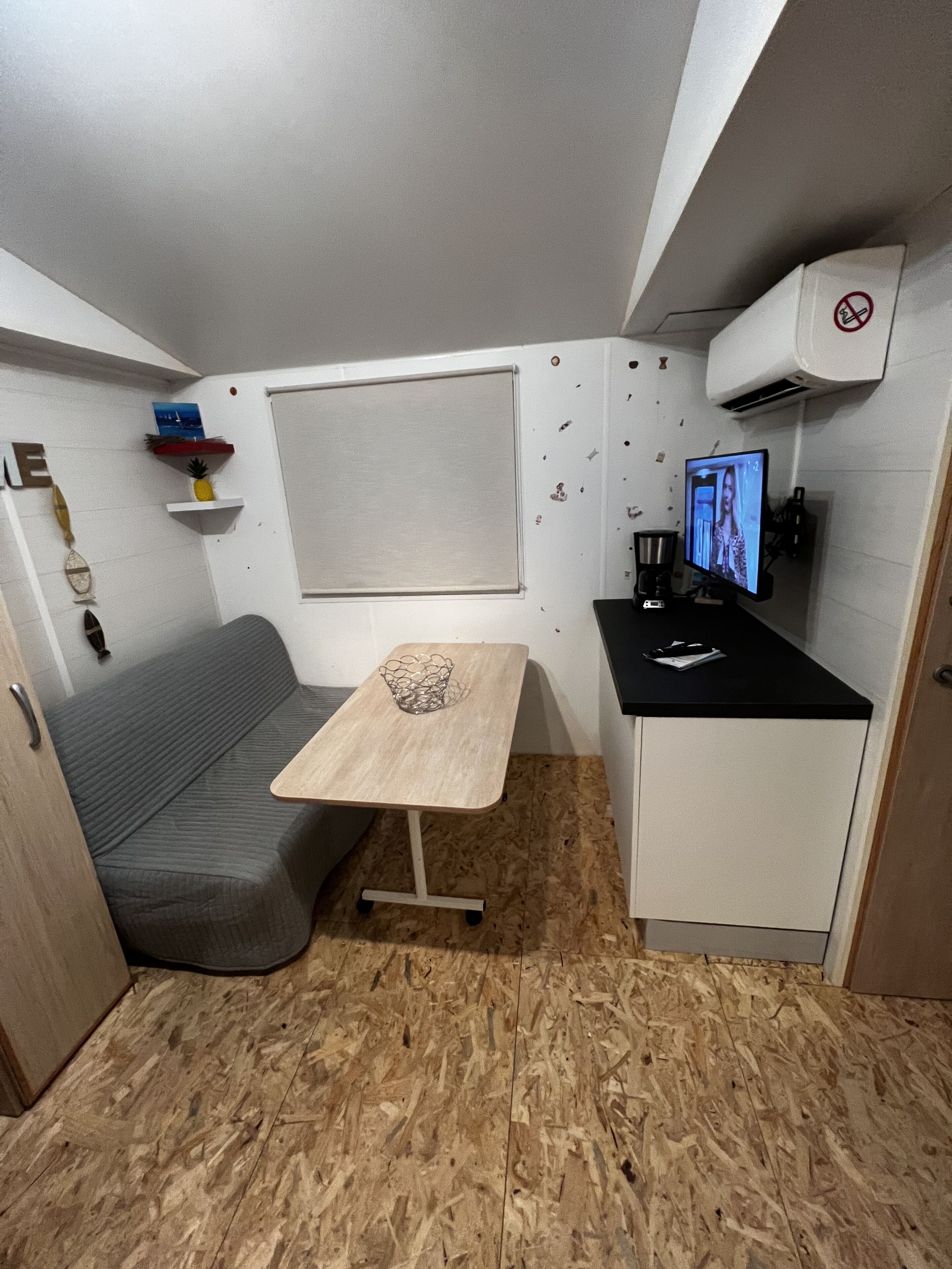 Una kitchenette compacta con una pequeña mesa, un sofá y un televisor.