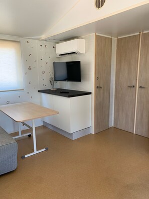 Uma cozinha compacta com televisão de tela plana, uma mesa pequena e um sofá.