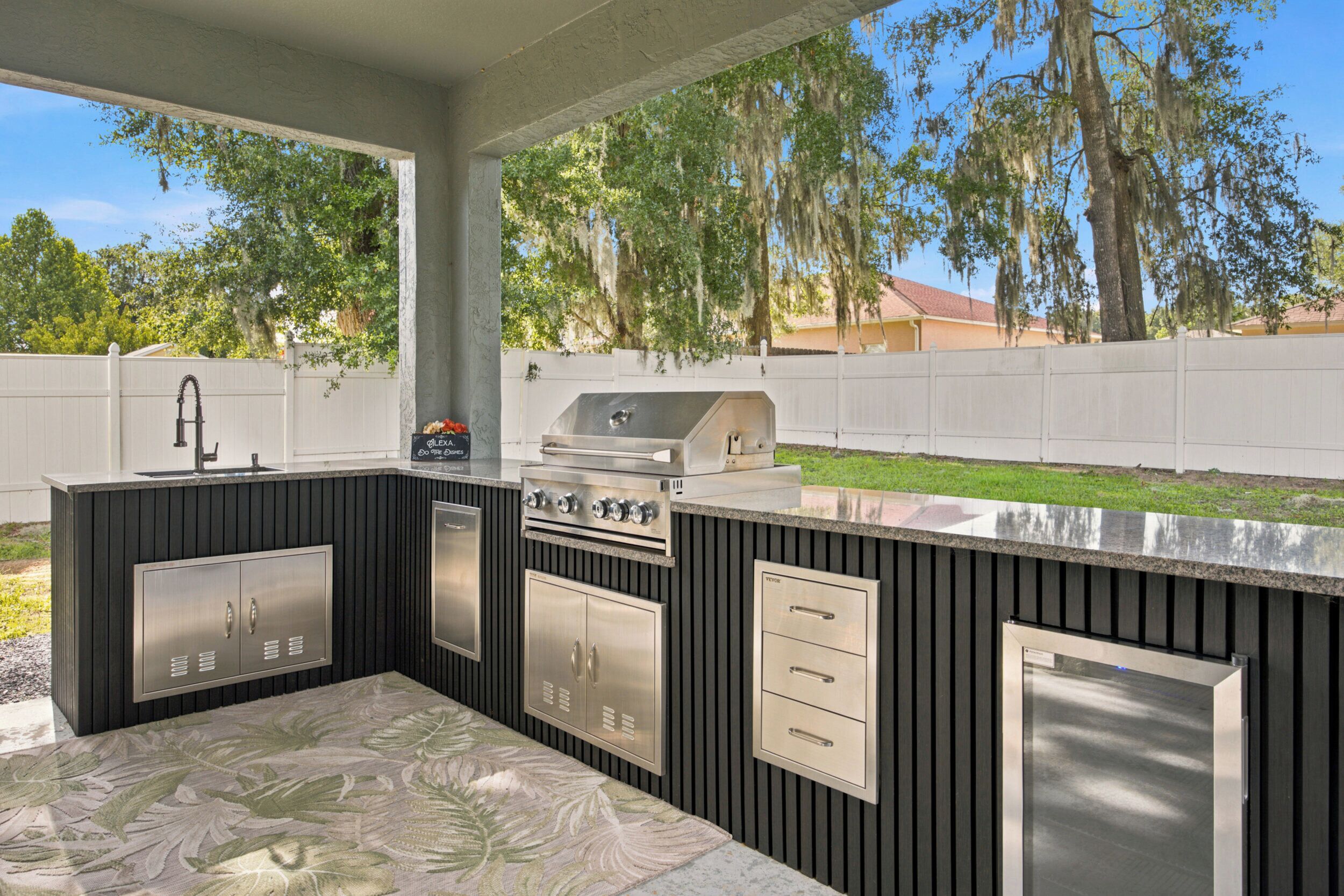 Una cocina al aire libre con parrilla, pileta y alacenas.