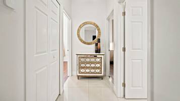 A hallway with white doors, a round mirror, and a wooden dresser with drawers.