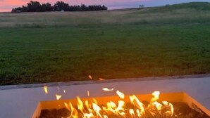Bålsted i et åbent landskab med solnedgang i baggrunden.