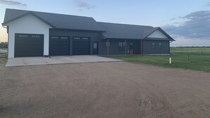 En toetages bygning med garage, overdækket veranda og indkørsel.