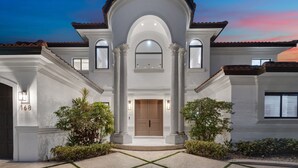 A two-story house with a central entrance, large columns, and a tiled roof. - WATERFRONT MANSION (Fort Lauderdale)