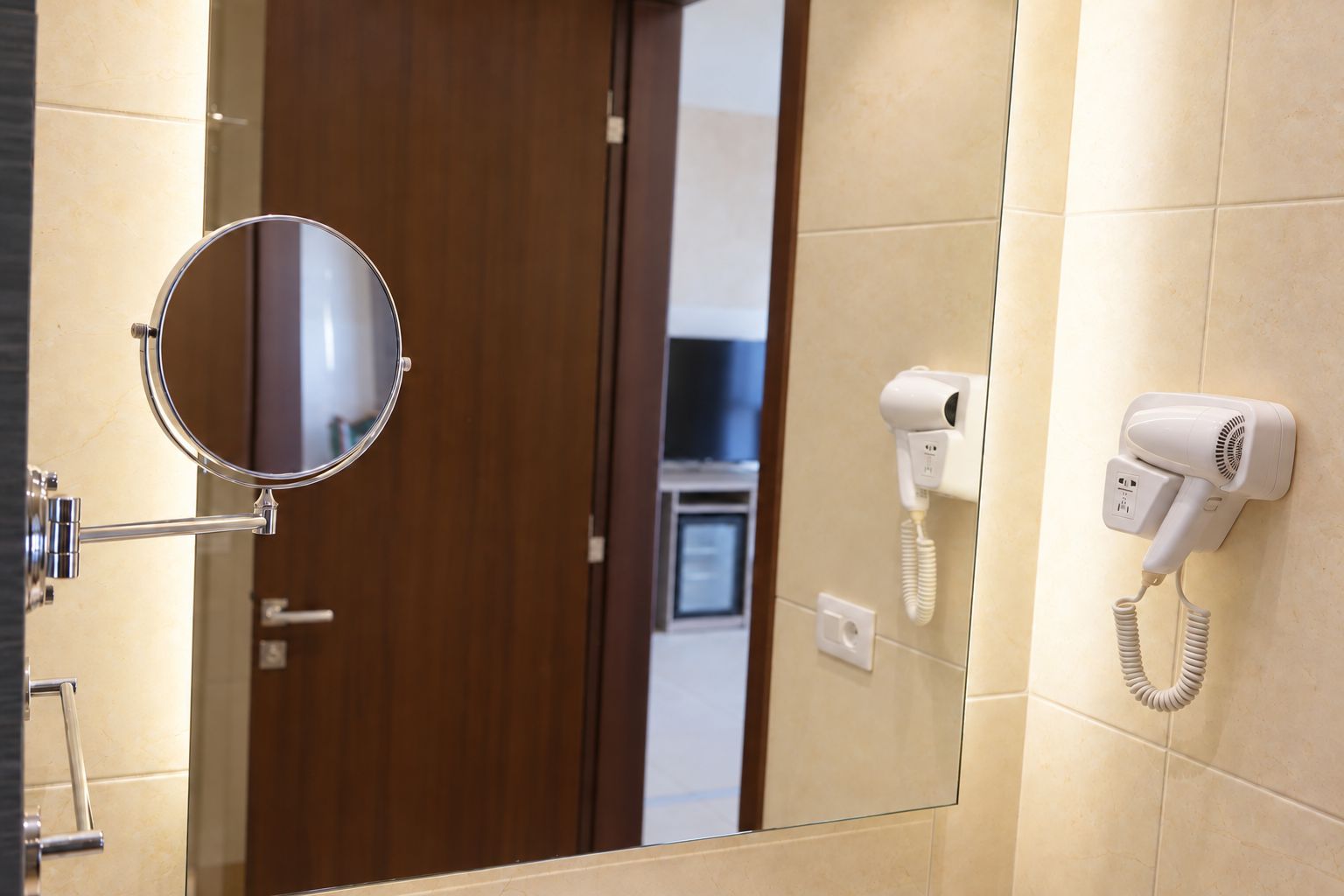 Un baño con un espejo redondo, un secador de pelo y un perchero para toallas.