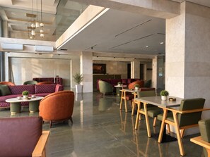 A modern interior with seating areas, tables, and a staircase. - Byblos Gate Hotel (Byblos)