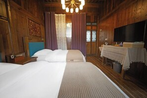 Una habitación de madera con una cama, cortinas, una mesa con mantel y un televisor.