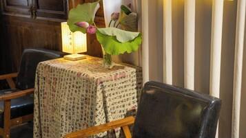 A table with a patterned tablecloth, a vase with a plant, and a lamp.