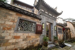A traditional building with a tiled roof, a stone wall, and a sign with Chinese characters. - Building A, Futongyuan Inn, Tianqi Hongcun, Huangshan (Yi County)