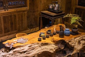 A wooden dining table with various ceramic items, a potted plant, and a rustic wooden chair. - Building A, Futongyuan Inn, Tianqi Hongcun, Huangshan (Yi County)