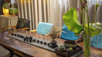 A wooden table with a tea set, a bonsai, and a vase with flowers.