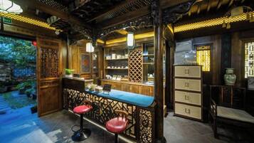 A traditional-style bar area with a counter, stools, and shelves.