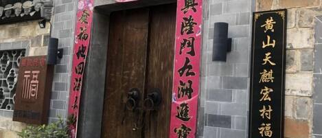 A traditional building with a wooden door, stone walls, and multiple signs with Chinese characters.