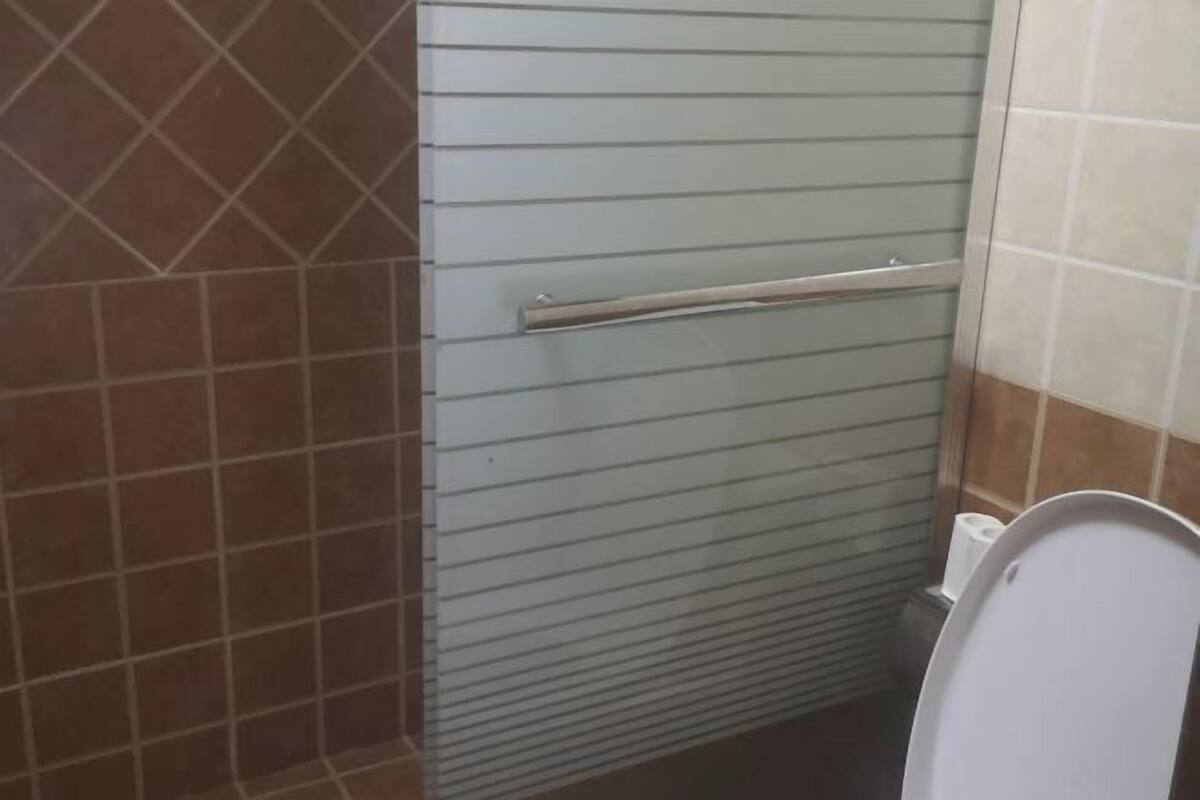 Un baño con inodoro, toallero y paredes con azulejos.