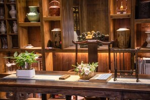 Une table en bois sur laquelle se trouvent un vase de fleurs, un panier et un livre.
