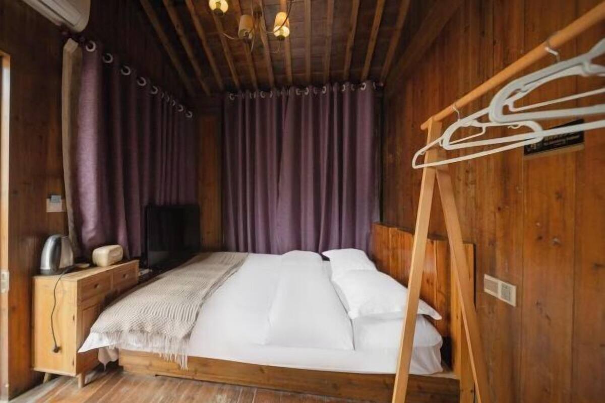 Una habitación de madera con una cama, un televisor y un aparador de madera.