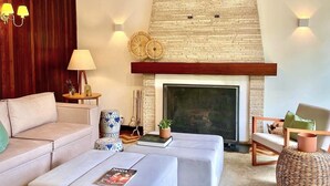 A modern living room with a fireplace, a sofa, a coffee table, and a fireplace mantel with decorative items. - Casa Três Rios - Campos do Jordão (Campos do Jordão)
