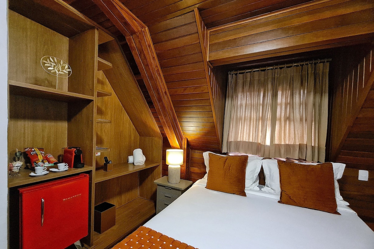 A wooden room with a bed, a red cabinet, a lamp, and a window with curtains.