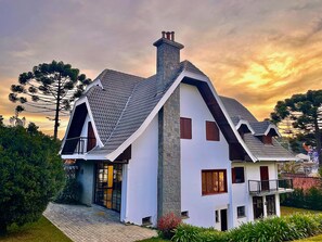 Una casa moderna de dos pisos con techo inclinado, fachada de piedra y un balcón.
