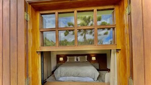 A bedroom with a large window, a bed, and a nightstand. - Casa Três Rios - Campos do Jordão (Campos do Jordão)