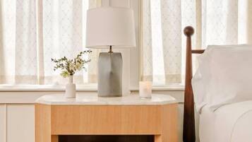 Ein ordentlich eingerichteter Nachttisch mit Lampe, einer kleinen Blumenvase und einer Kerze.