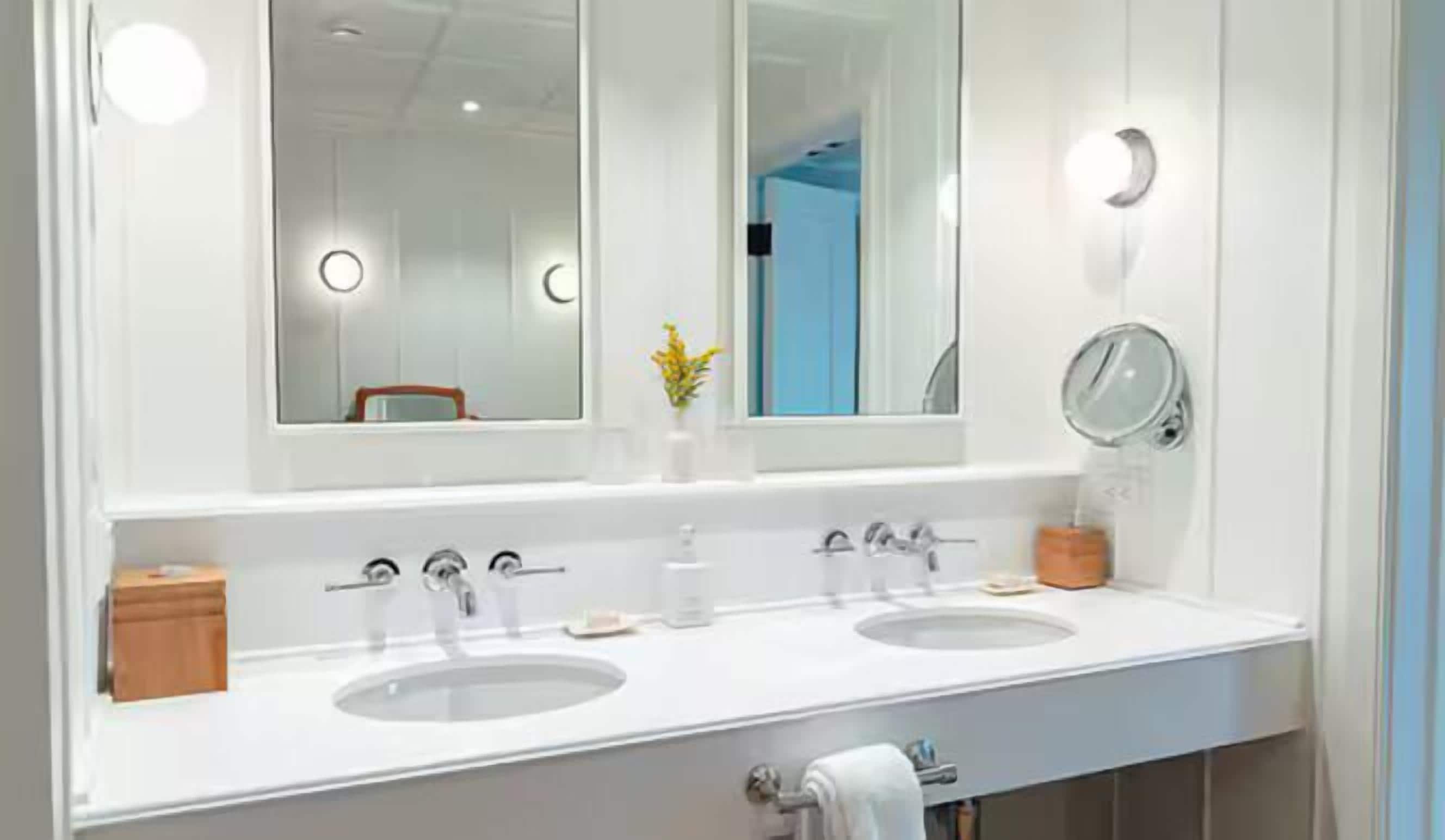 A bathroom with two sinks, a mirror, and a towel rack.