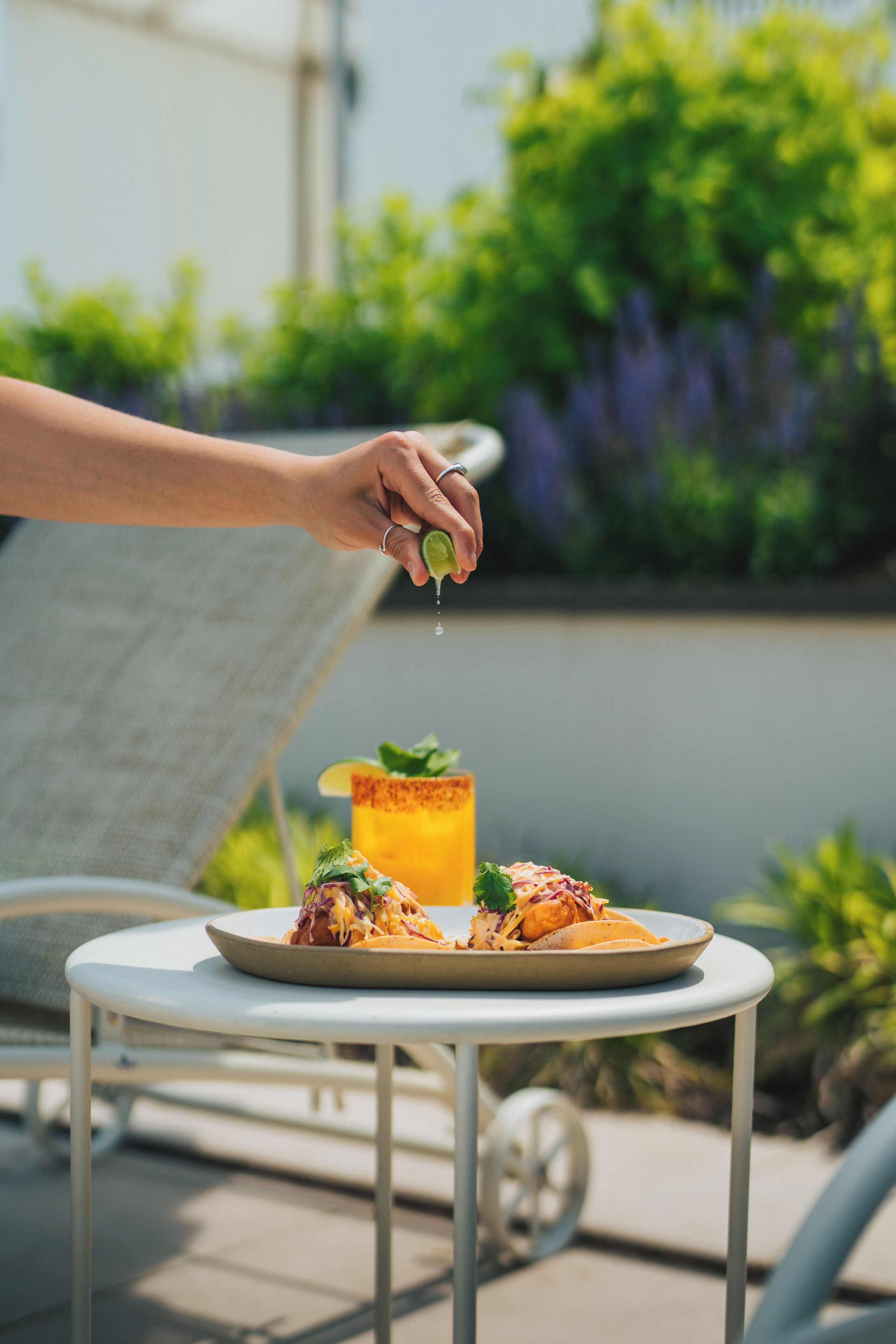 Una mesa con un plato de comida y una bebida, al aire libre con vegetación de fondo.