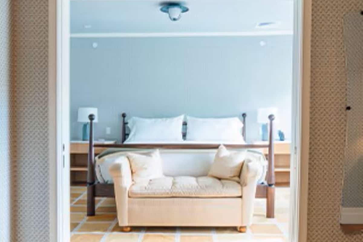 Une pièce comprenant un lit, un canapé et une chaise. Une porte donne accès à une autre pièce.