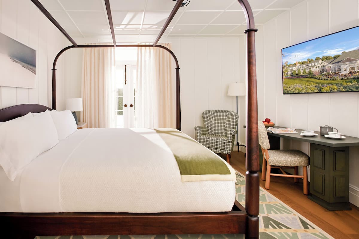 Un lit à baldaquin avec une tête de lit, un bureau avec une chaise, une lampe et un tableau accroché au mur.