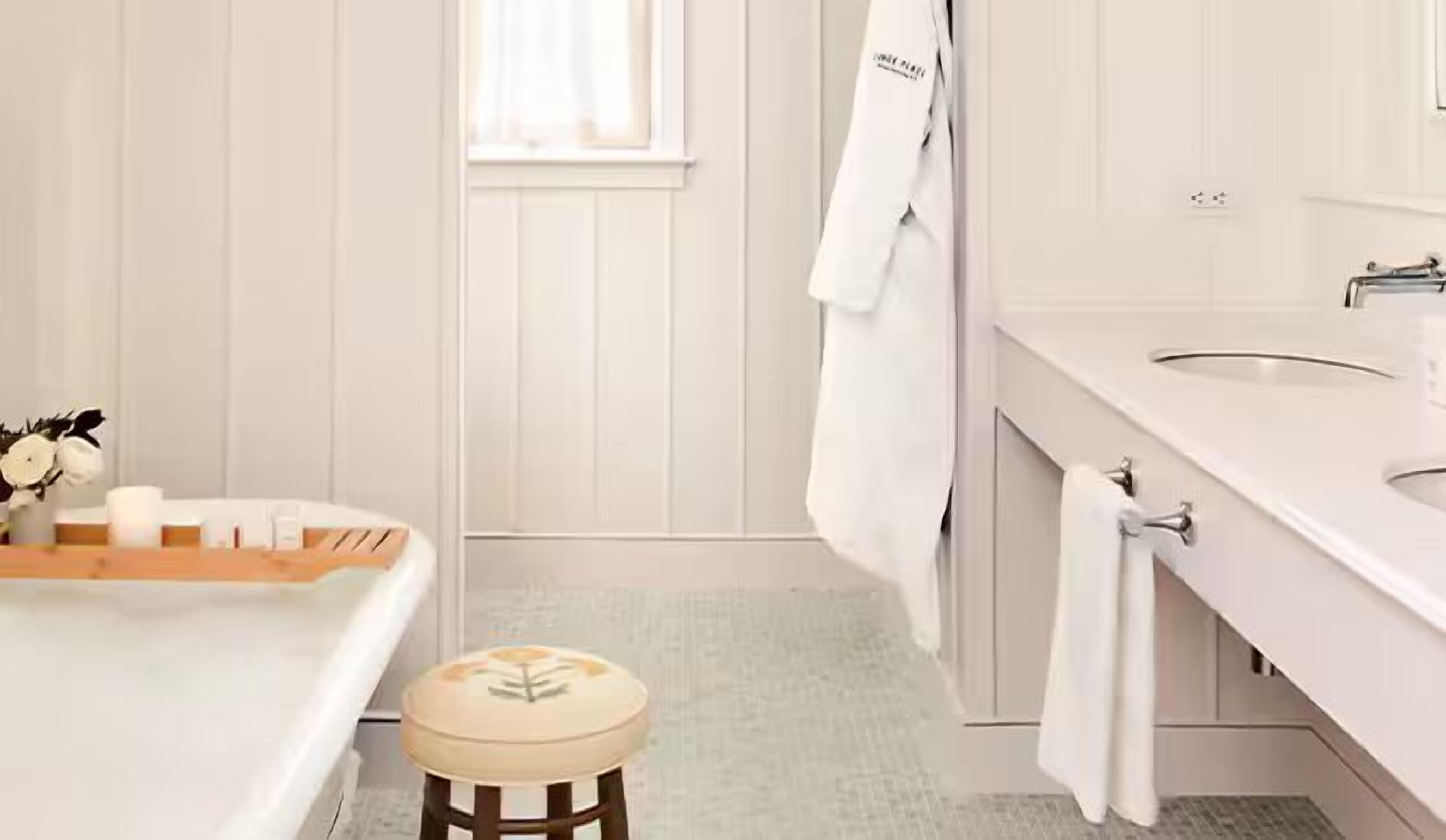 Un baño con un lavamanos blanco, un espejo y un taburete de madera.