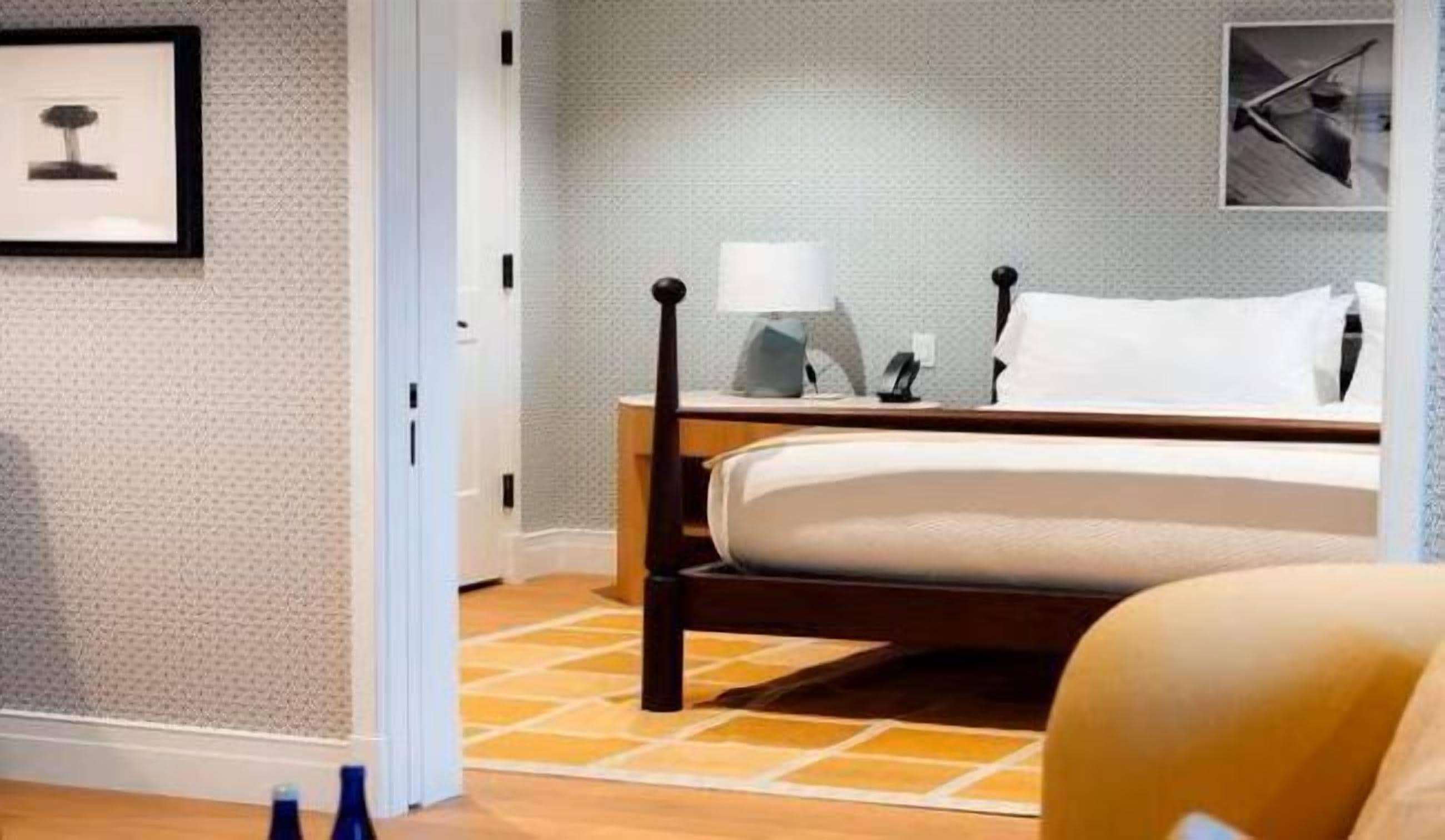 A hotel room with a bed, a nightstand, a lamp, and a framed picture on the wall.