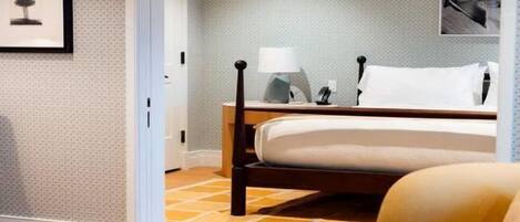 A hotel room with a bed, a nightstand, a lamp, and a framed picture on the wall.