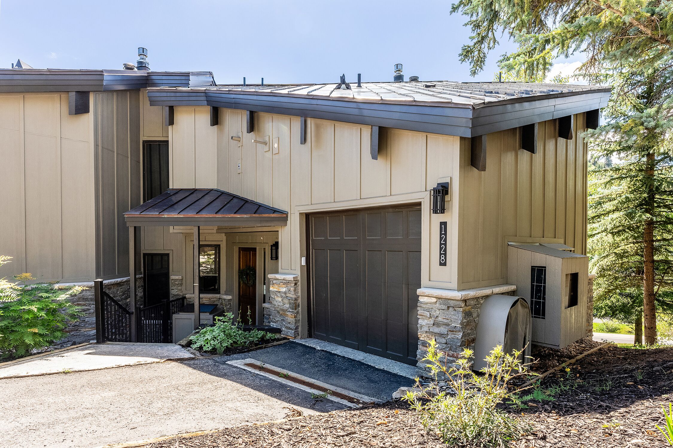 A modern two-story house with a garage, a covered entryway, and a small utility shed.