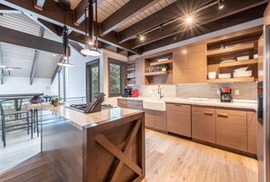 Una cocina moderna con armarios de madera, encimera de mármol e iluminación colgante.