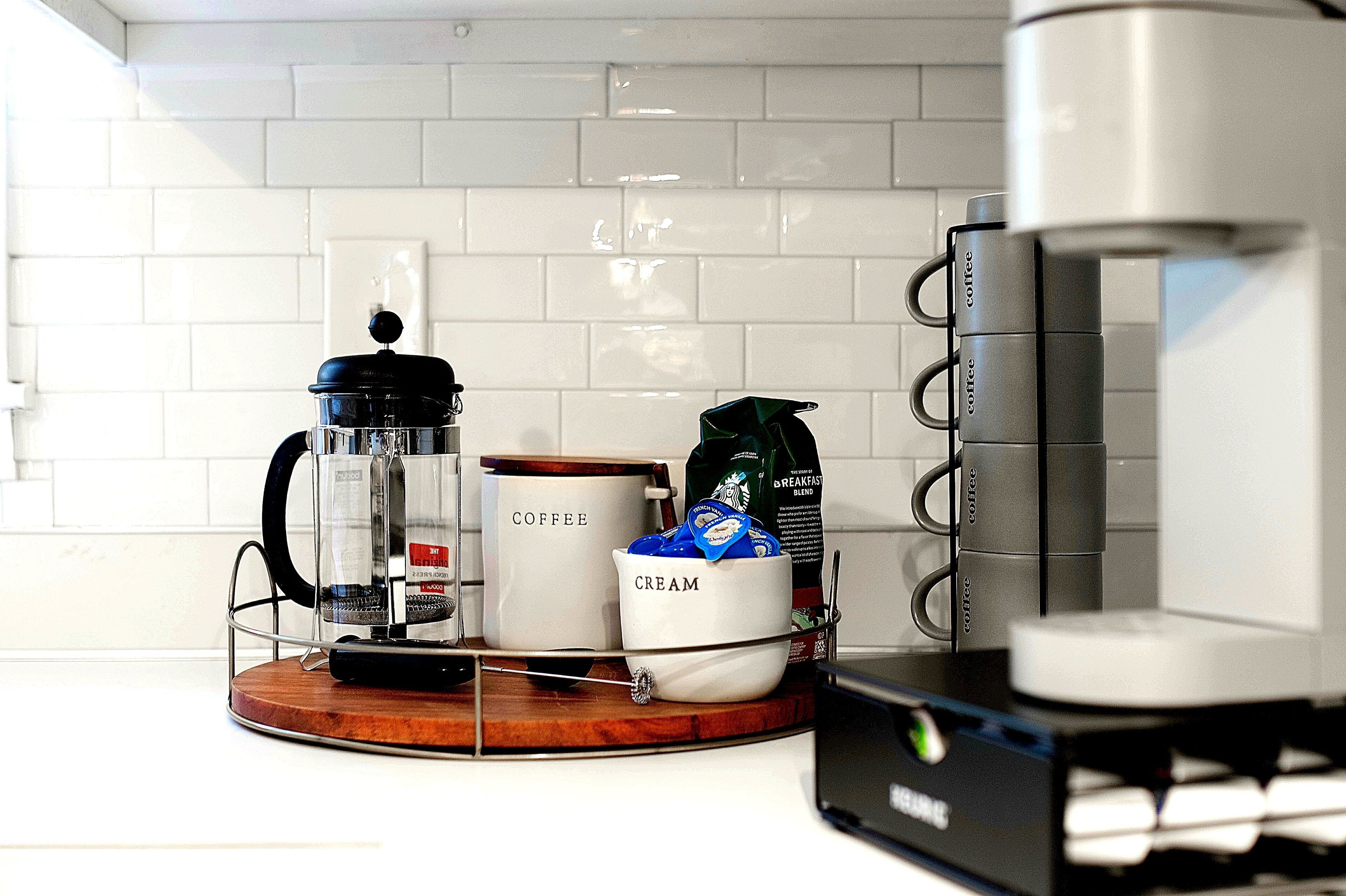 Eine Küchenarbeitsplatte mit Kaffeemaschine, French Press, Kaffeemühle und Kaffeepackung.