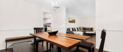 A modern dining area with a wooden table and chairs, a bench, and a hanging light fixture.