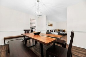 A modern dining area with a wooden table and chairs, a bench, and a hanging light fixture.