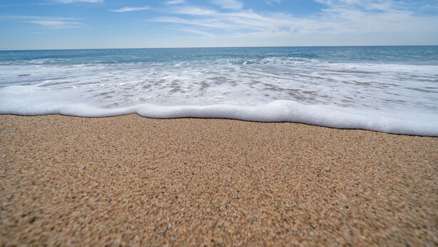 A beach with a sandy shore and gentle waves.