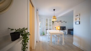 A modern living room with a dining area, a TV, and a plant.