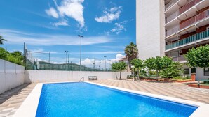 A swimming pool with a clear blue water surface, surrounded by a white wall and a tiled deck.