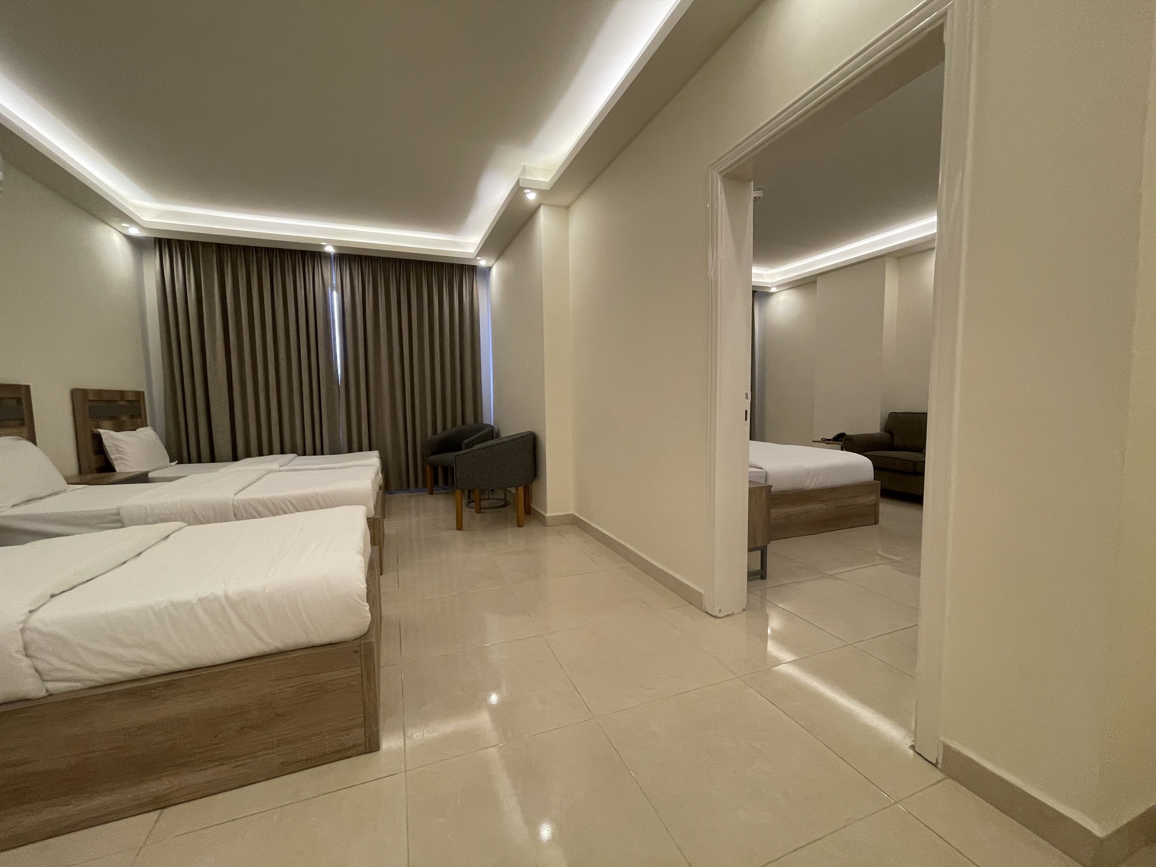 A hotel room with two beds, a desk, a chair, and a sofa.